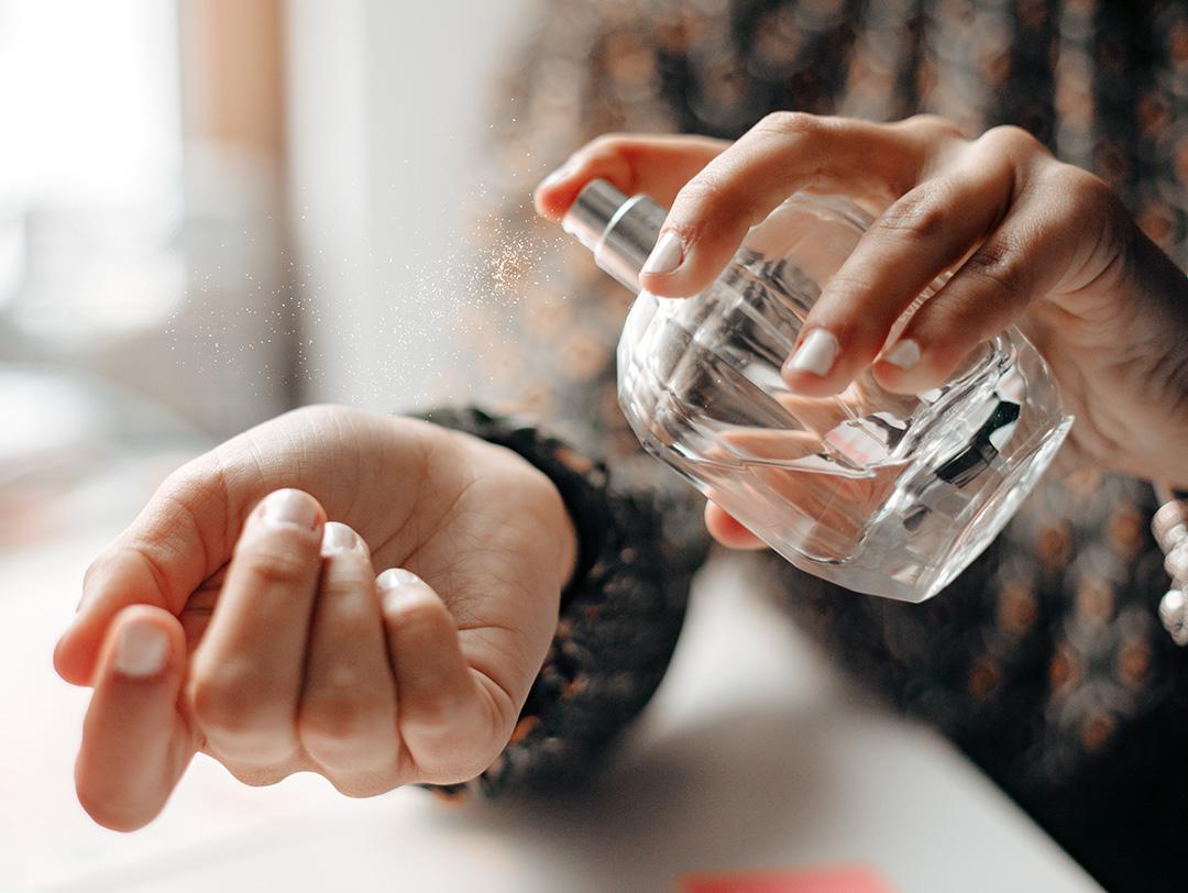 A photo showing the particles of a sprayed perfume onto the hands Desktop
