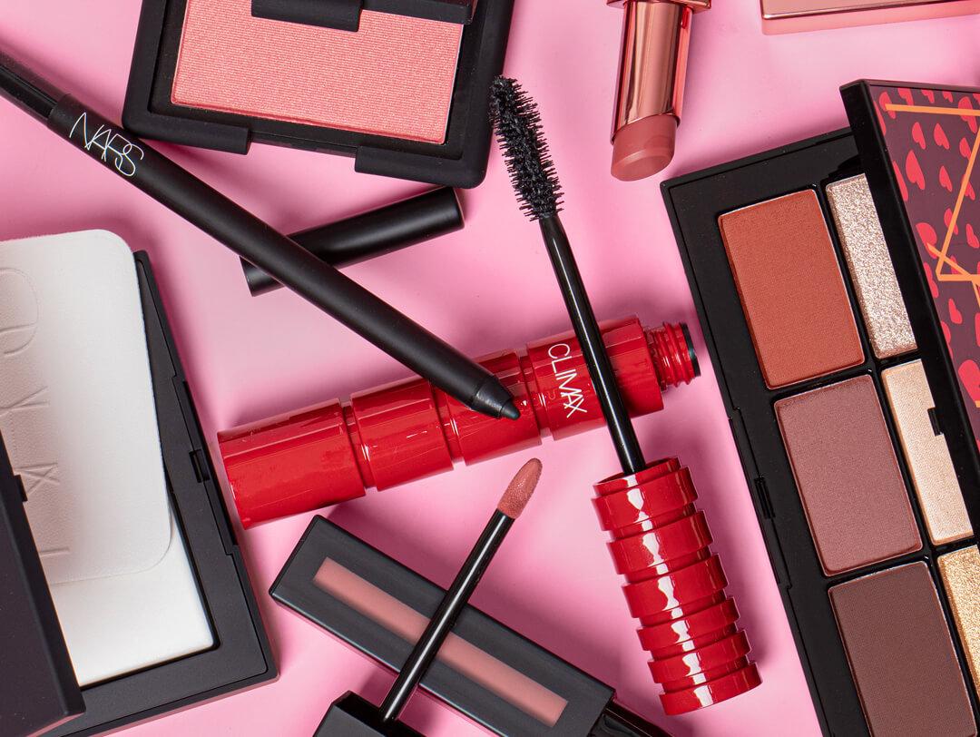 Different makeup products scattered on pink background Desktop