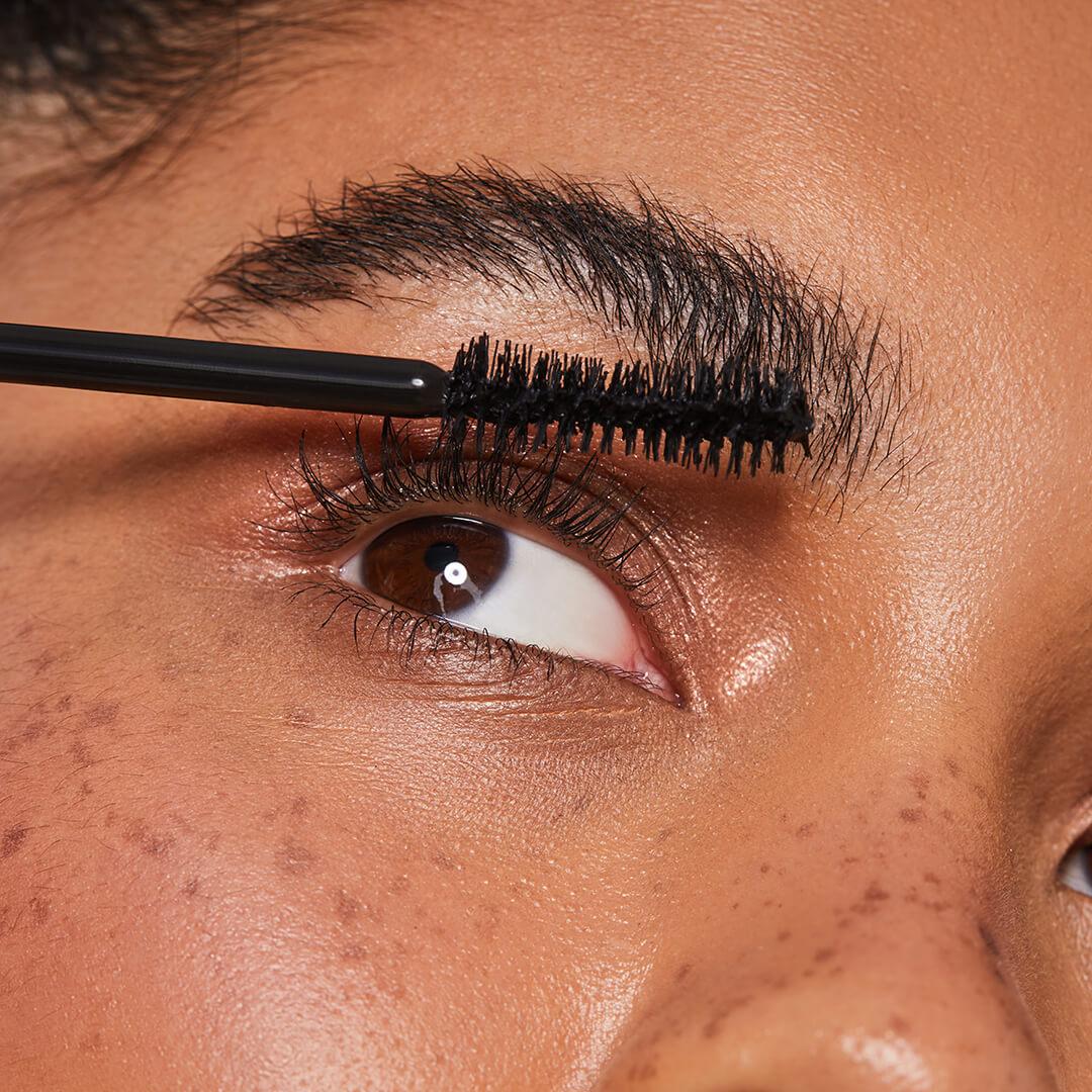 Close-up image of a model putting on mascara Desktop