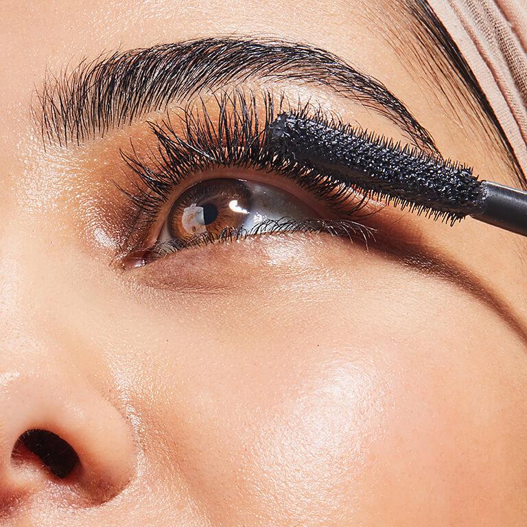 A closeup image of a model wearing neutral eyeshadow putting on mascara and an image of BRIOGEO Hair Care B. Well Organic + Cold-Pressed 100% Castor Oil Mobile