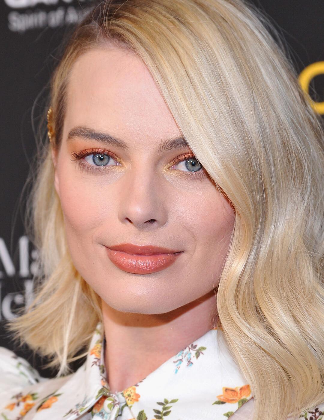 Margot Robbie rocking a soft orange eyeshadow look and floral shirt Mobile