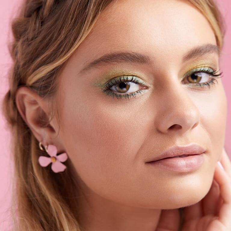 A close-up image of a model wearing a shimmery lime green and mint green eyeshadow look paired with a nude pink lipstick Desktop