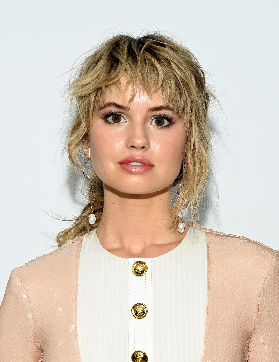 An image of Debby Ryan sporting her shag-meets-mullet hairstyle wearing a peach long sleeve dress with gold buttons Desktop