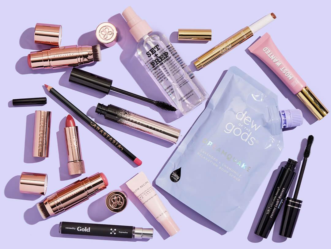 Skincare, makeup, and hair products and tools from various brands scattered on light purple background Desktop