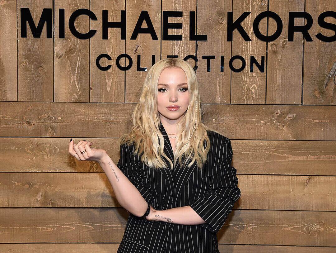A photo of Dove Cameron wearing a striped coat on a wooden background Desktop