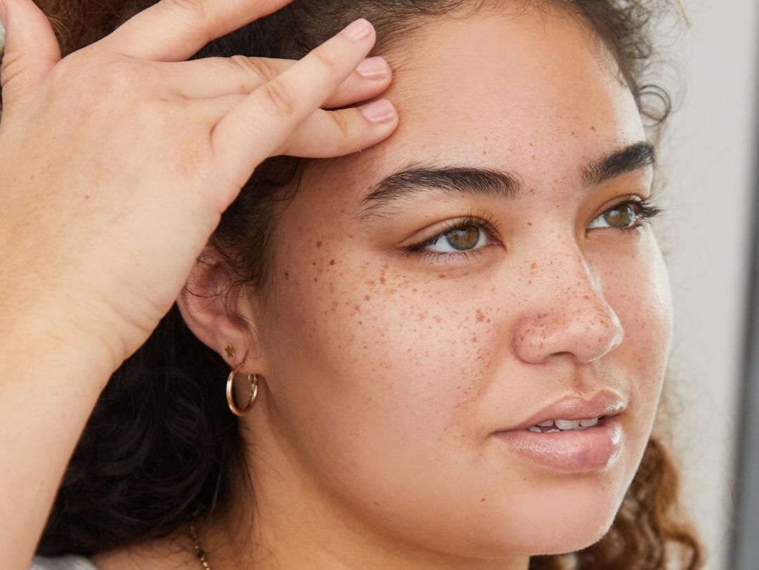Close-up image of a model touching her forehead with two fingers Desktop