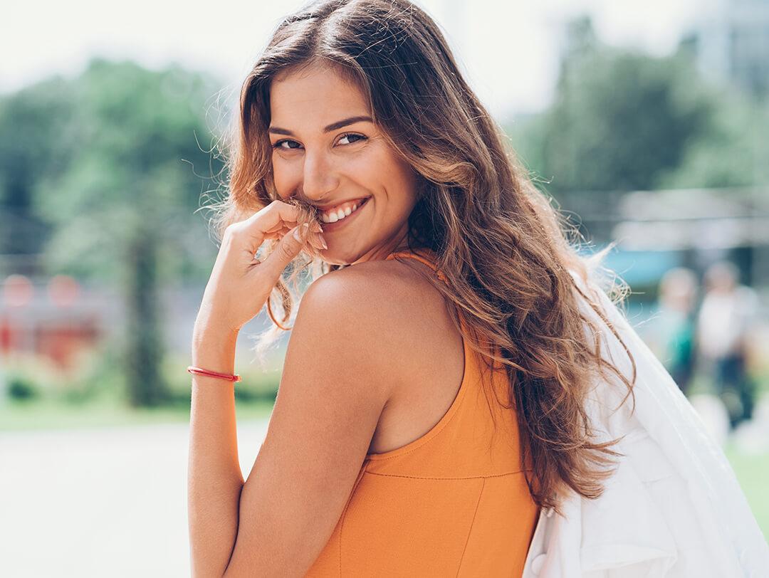 Playful pretty woman with wavy hair walking outdoors Desktop