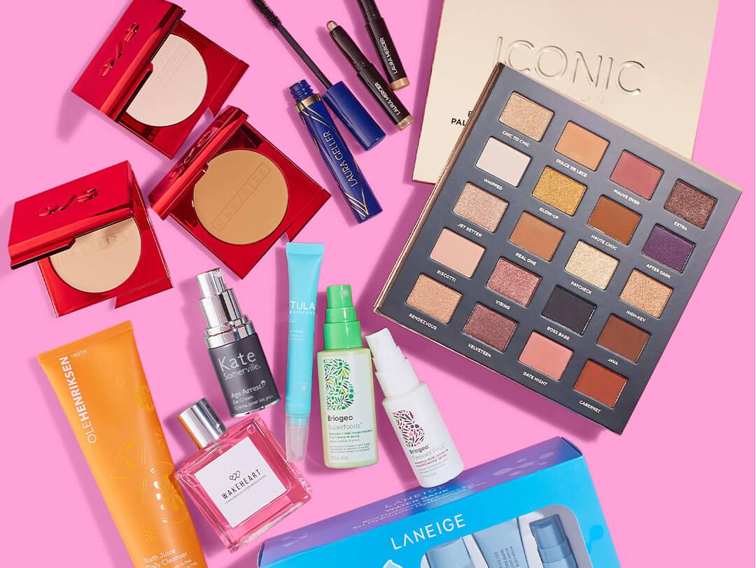 Various beauty brands and makeup products scattered on pink background Desktop
