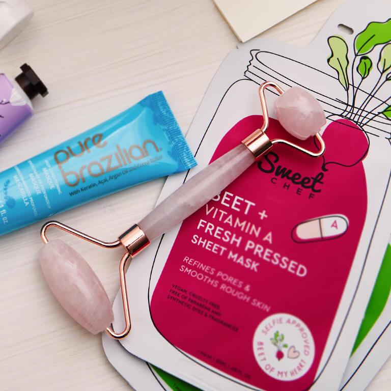 An image of a quartz roller on top of SWEET CHEF Fresh Pressed Sheet Masks with other skincare products Desktop