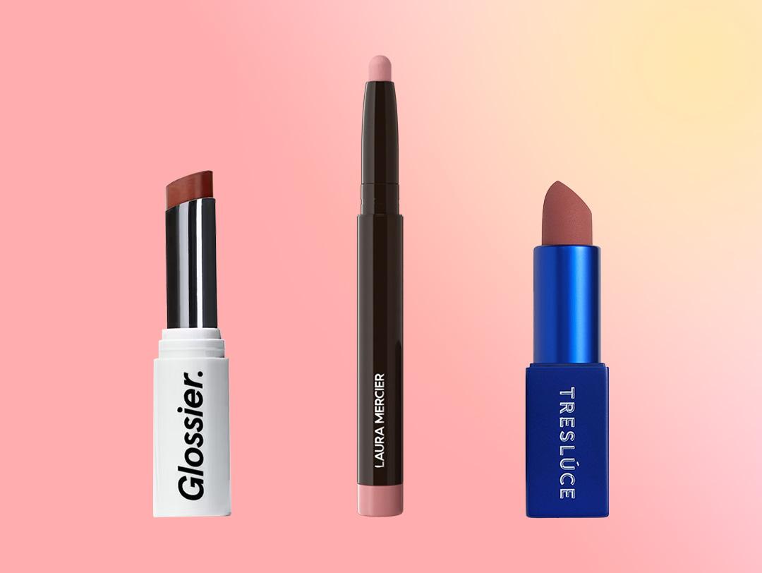 A flatlay of different nude lipstick products on a pink and peach gradient background Desktop