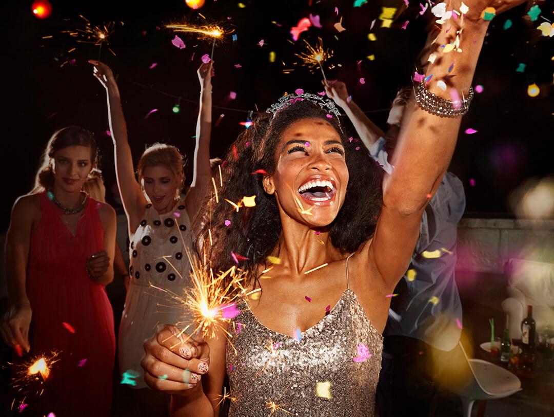 A picture of joyful women celebrating at a New Year's party holding sparklers, and enjoying the festive atmosphere with confetti Desktop