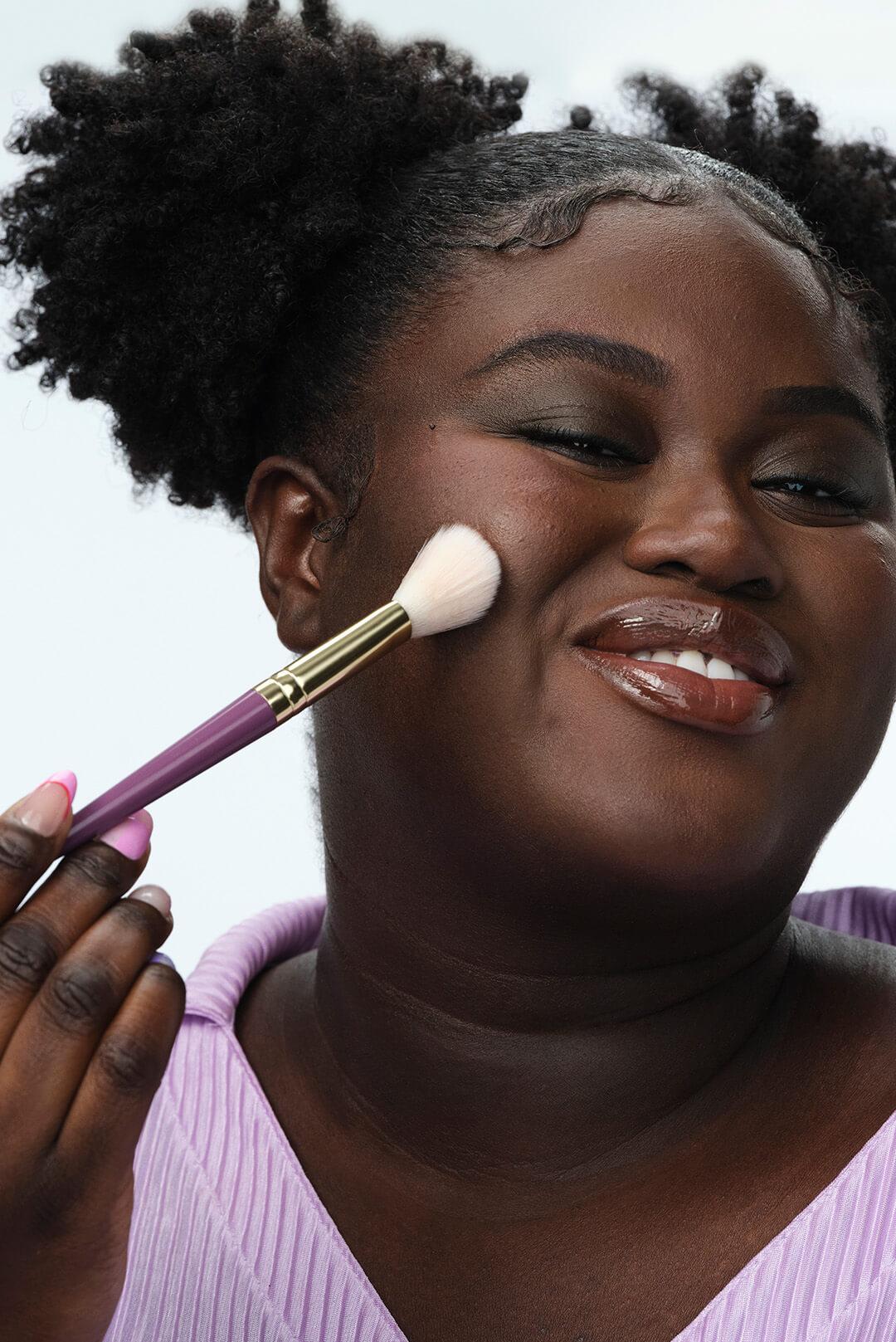 An image of a beautiful black woman with a make-up brush on her cheek against a white background Desktop