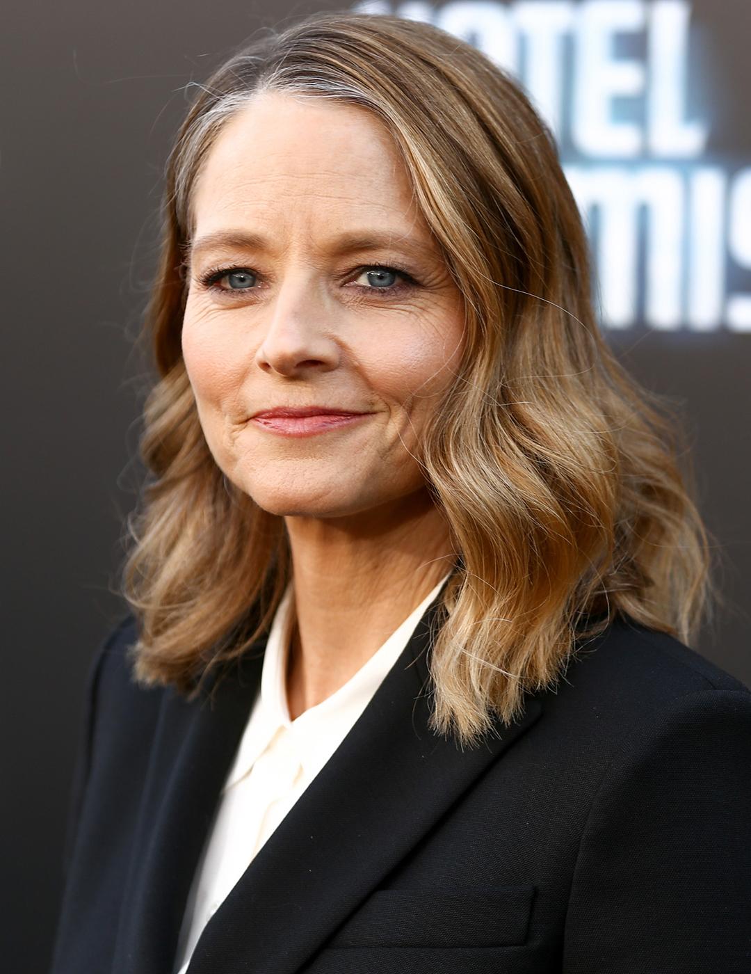A photo of Jodie Foster wearing a simple black pantsuit with her tousled shoulder length hair Mobile