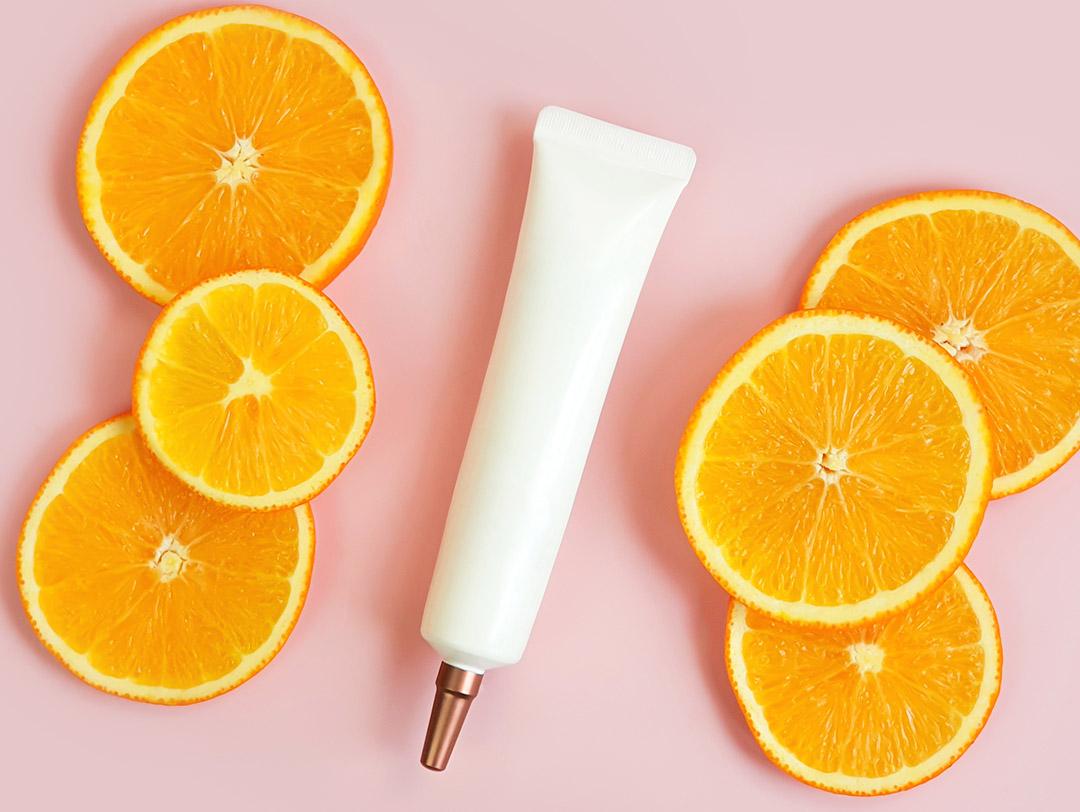 A photo of a serum with orange slices on a pink background Desktop
