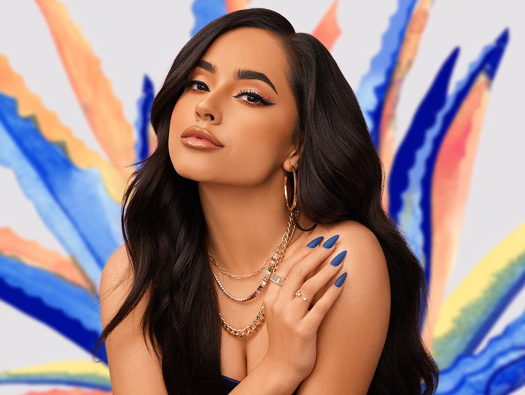 A glam Becky G posing against colorful background Desktop