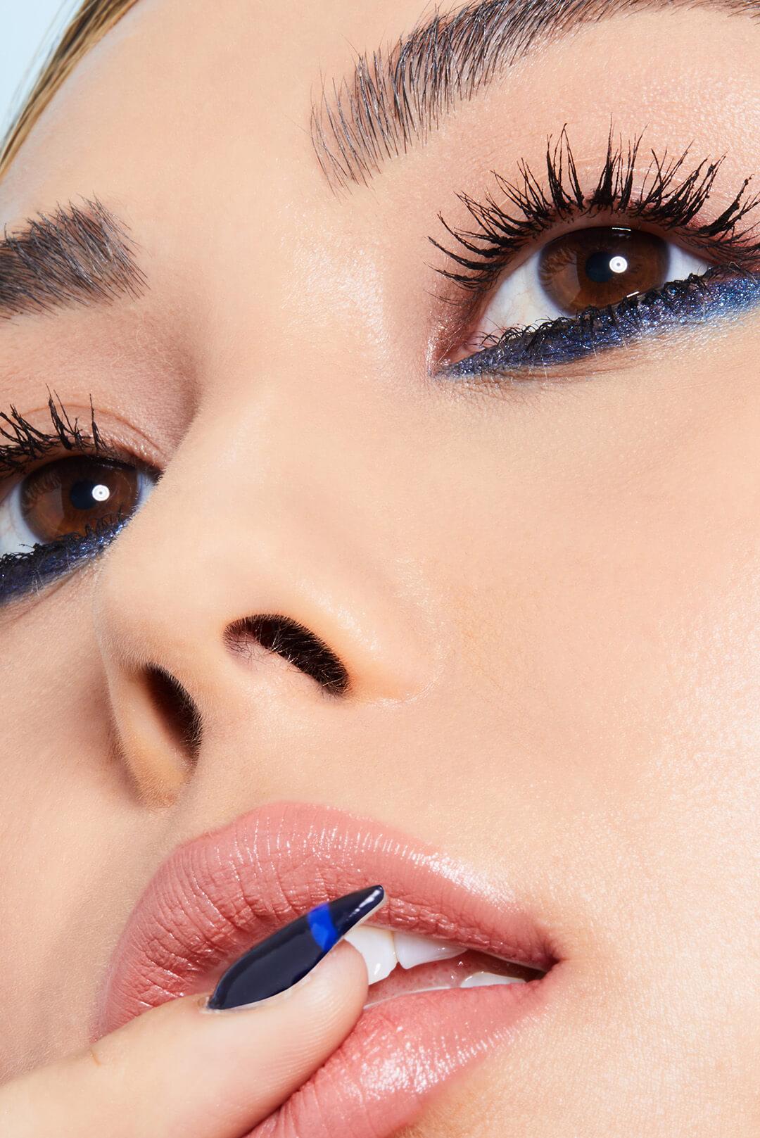 Close-up image of a model with a blue eyeliner and bold lashes makeup look Desktop