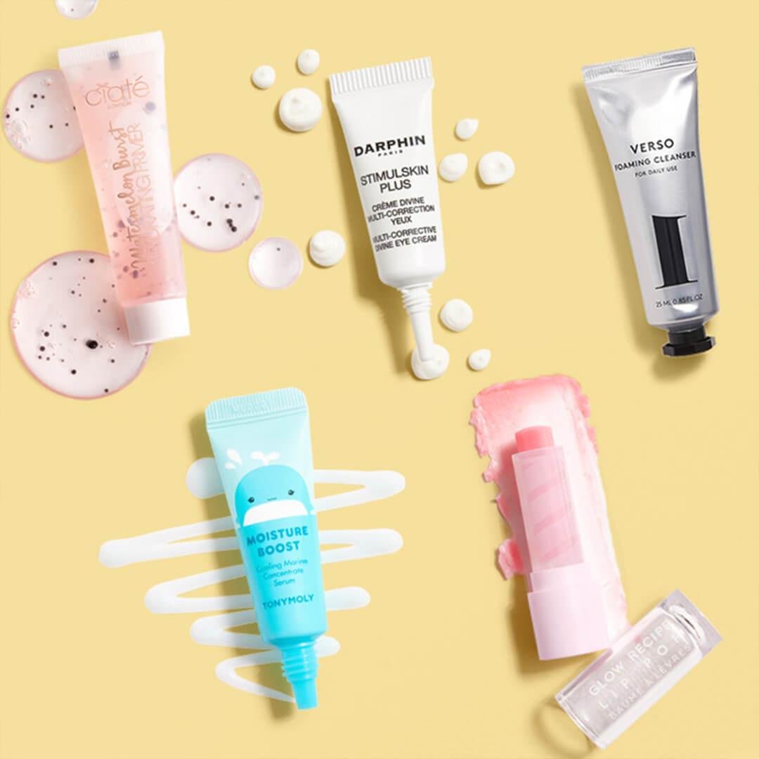 Skincare and makeup products from various brands swatched on yellow background Desktop