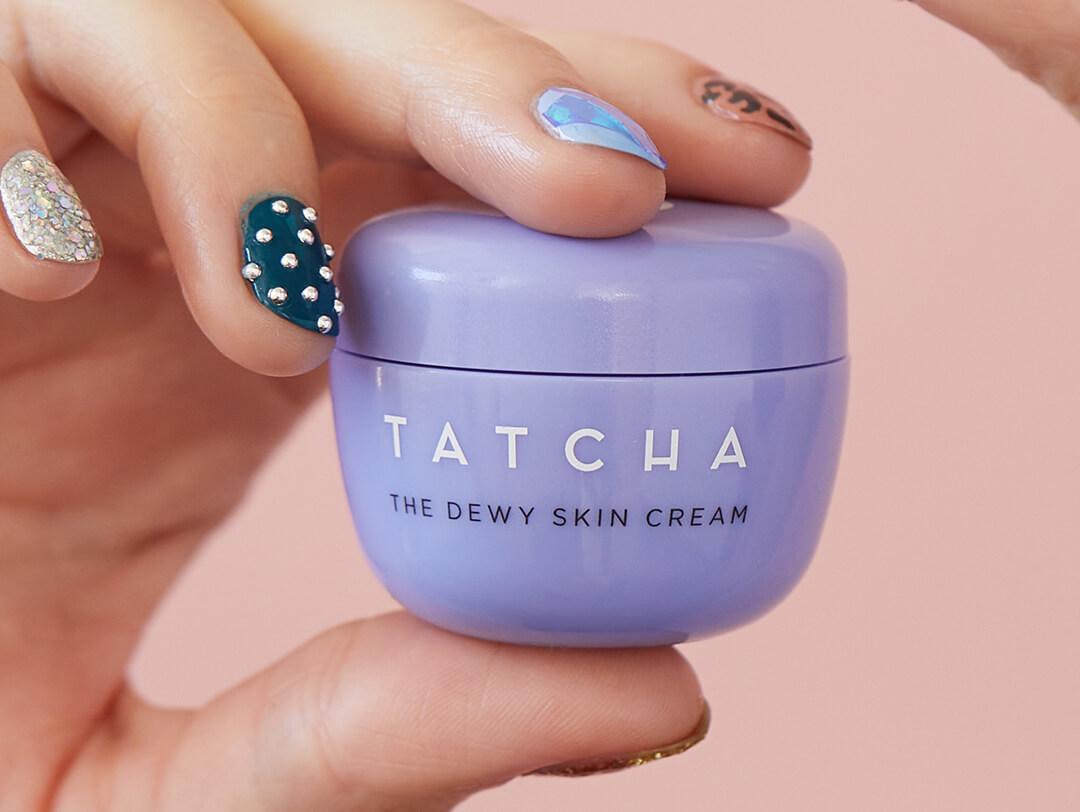 Close-up of a model's hand with bedazzled nail art holding the TATCHA The Dewy Skin Cream Desktop