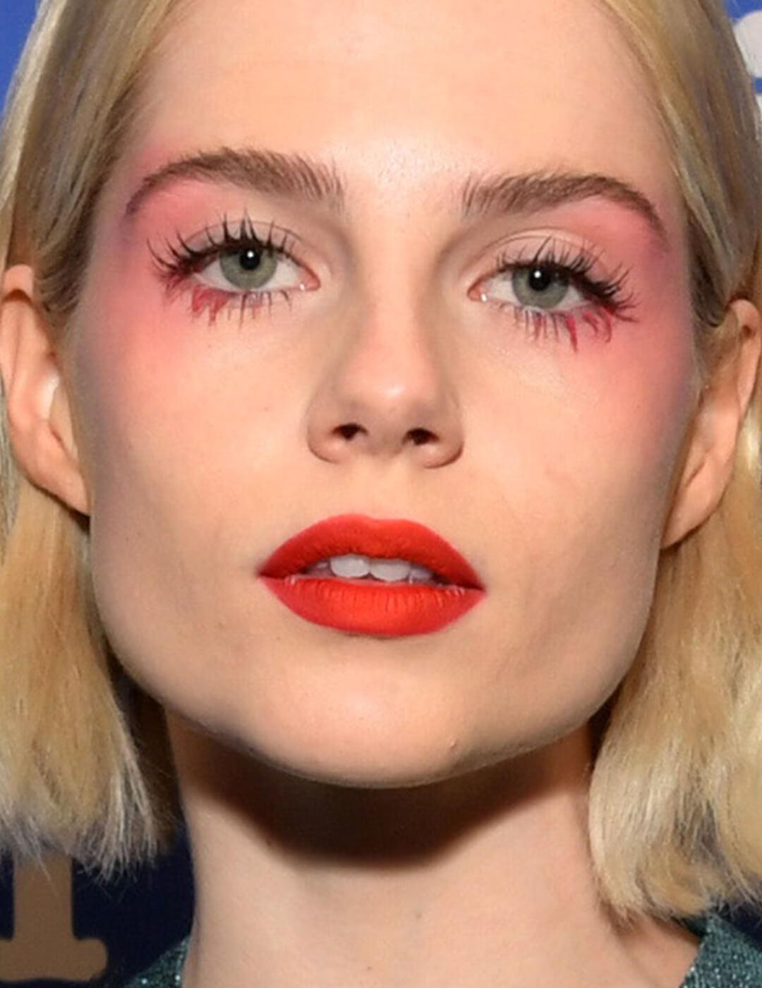 Lucy Boynton rocking a neon pink eyeshadow look and bold red lips Mobile