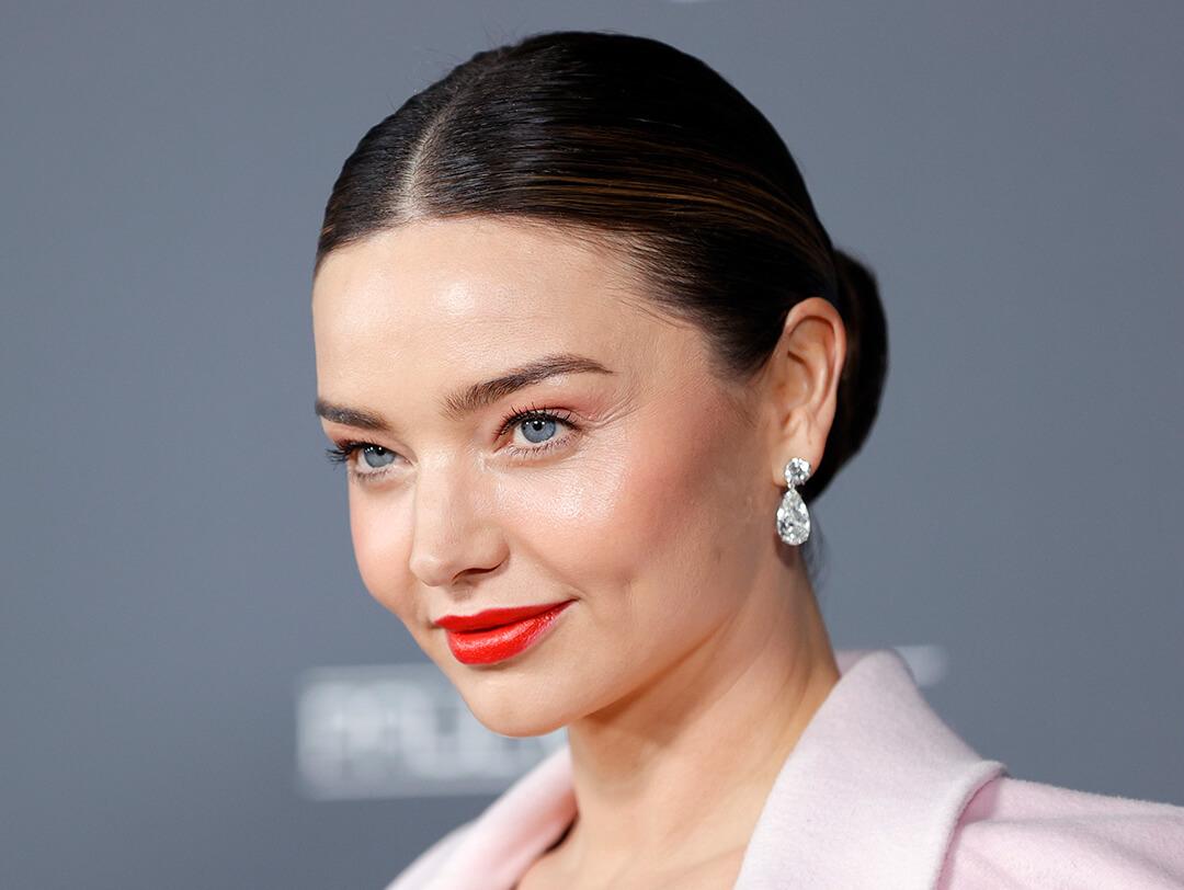 An image of Miranda Kerr looking fierce in her red lipstick while wearing a pink coat and a silver earring Desktop