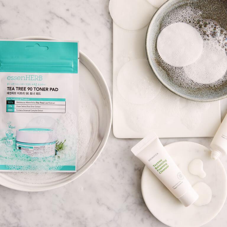 A flatlay image of tea tree oil skincare products on a marble surface Mobile