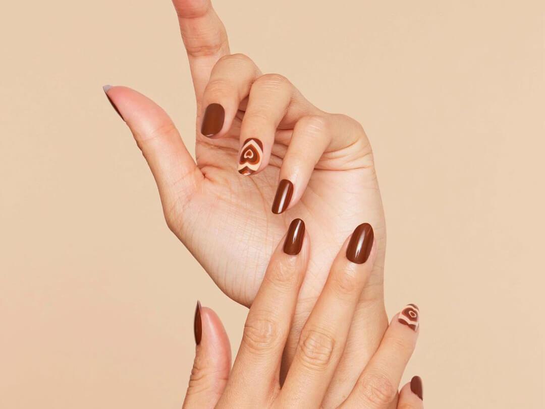 Close-up of model's hands with dark brown nail art and nail polish Desktop