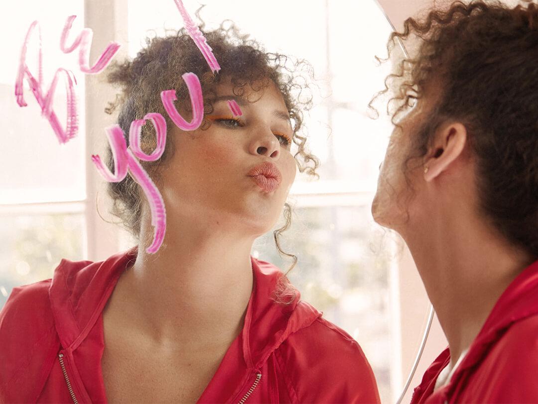 Image of a model pouting in front of a mirror with text written with a lipstick Desktop