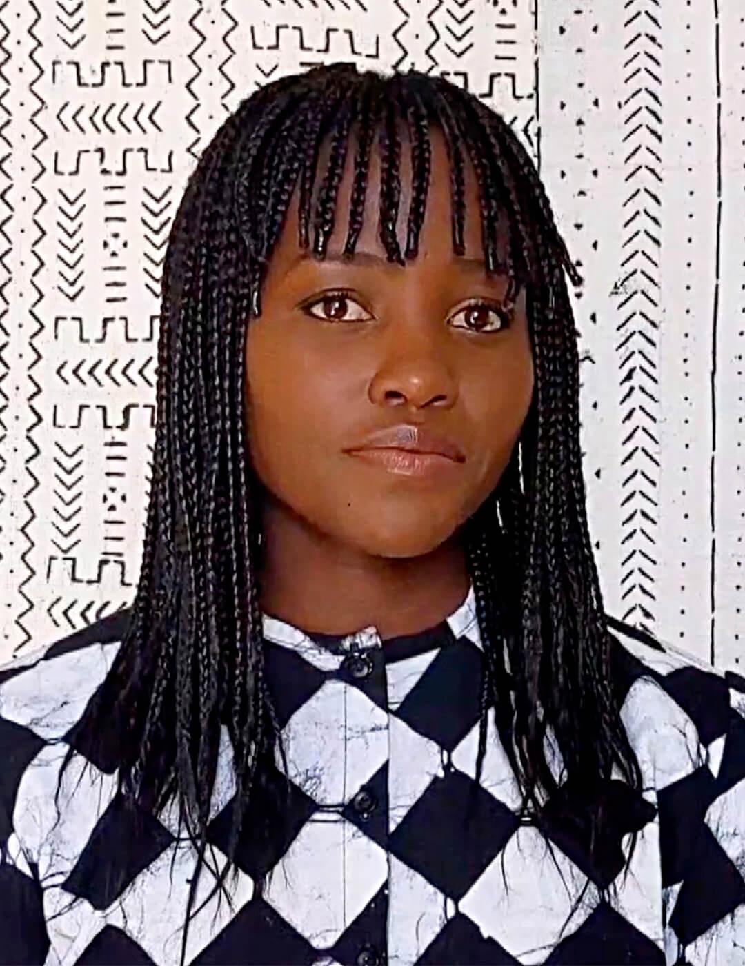 Lupita Nyong'o in a black and white geometric dress rocking a braided hairstyle with braided bangs Desktop