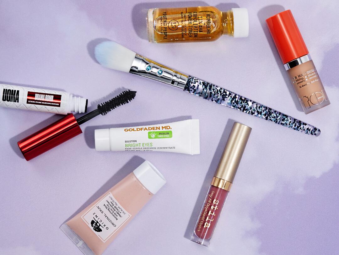 Makeup products and tools and skincare products on purple clouds background Desktop