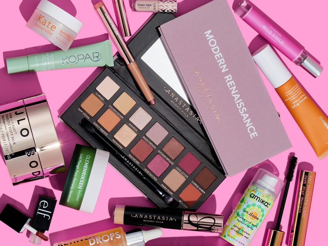 Skincare and makeup products from various brands scattered on pink background Desktop