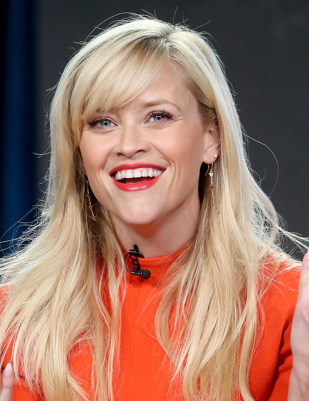 Smiling Reese Witherspoon rocking an orange dress and warm makeup look Mobile