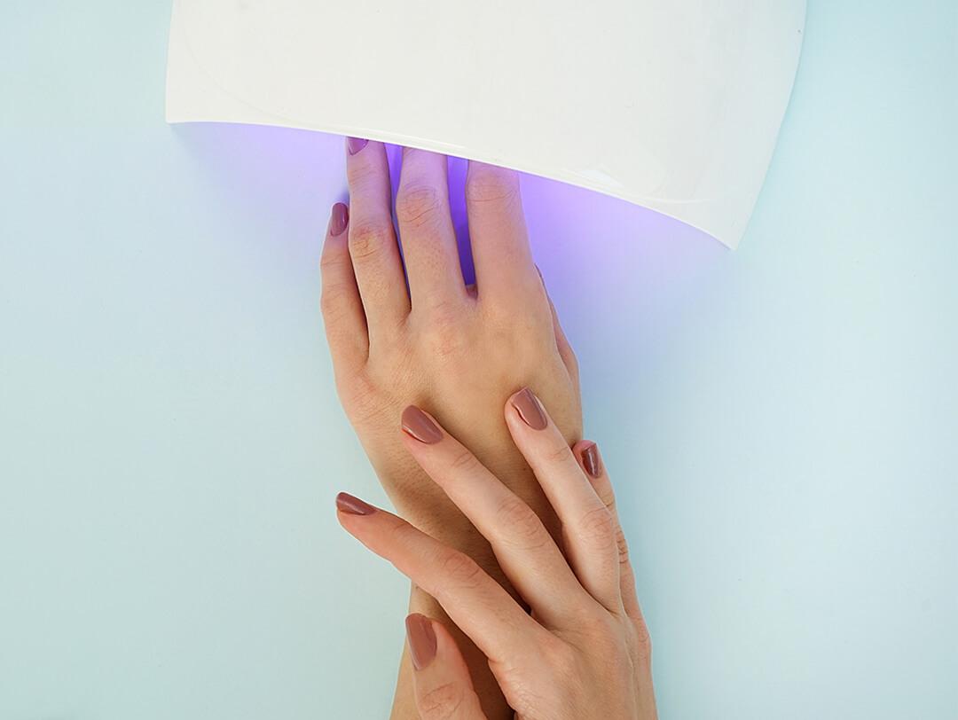 Close-up of a woman's hands drying her gel nail polish under a UV lamp Desktop