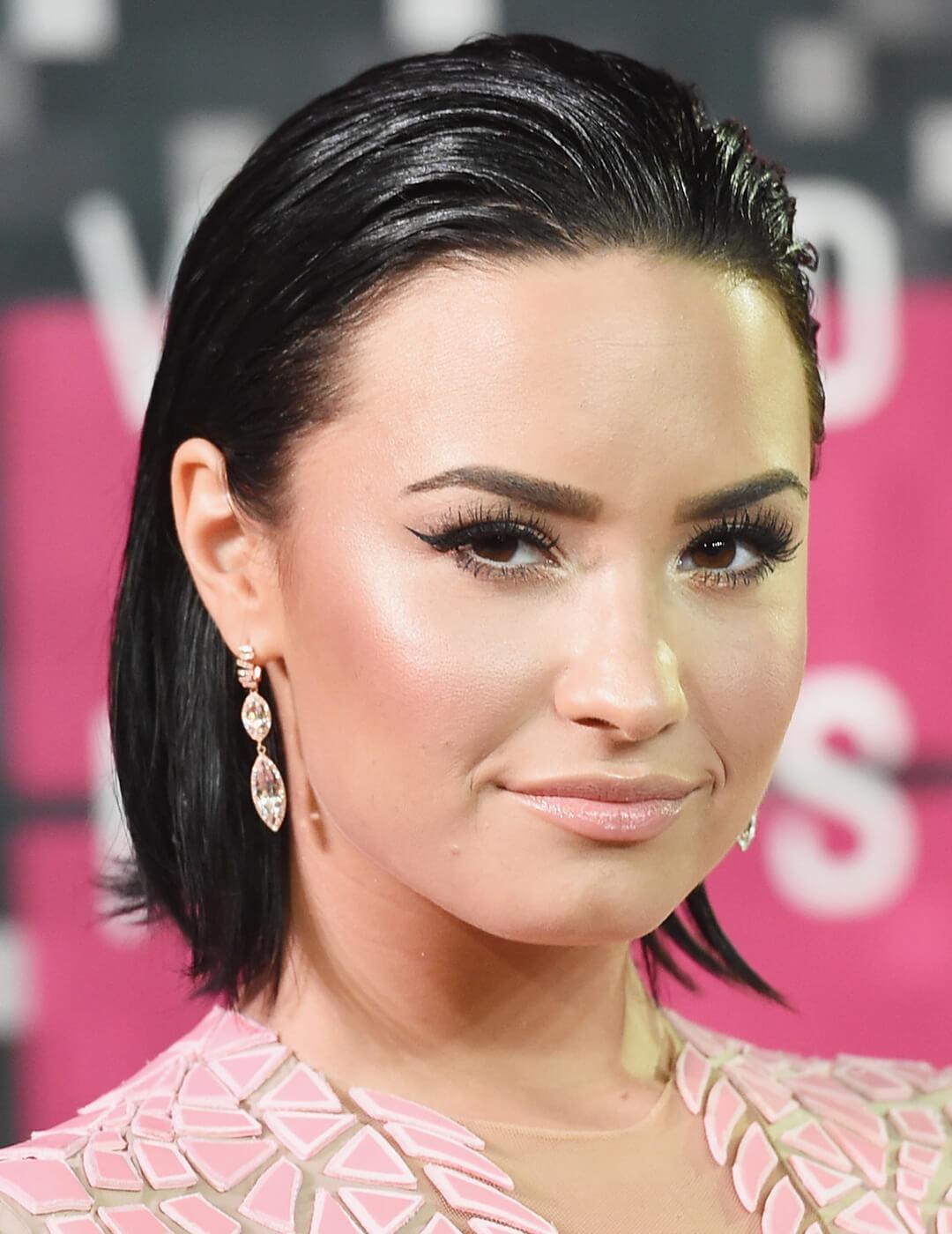 A photo of Demi Lovato showcasing her combed back, dewy look bob hair paired with an elegant earring Desktop