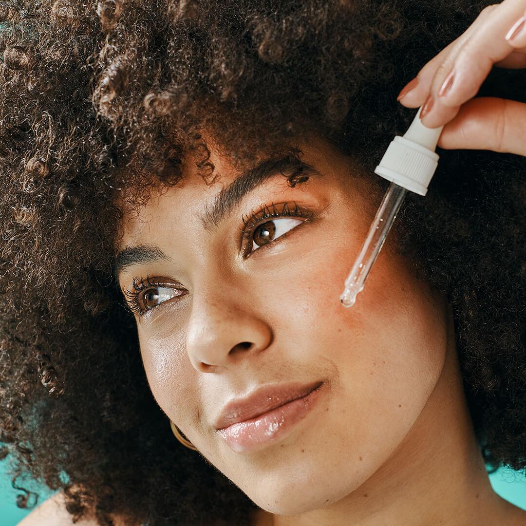 Closeup of a model applying serum on her cheek Mobile