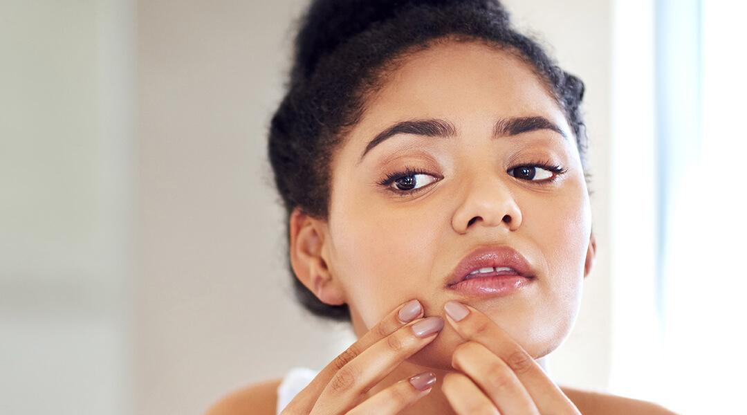 Young woman popping a zit Desktop