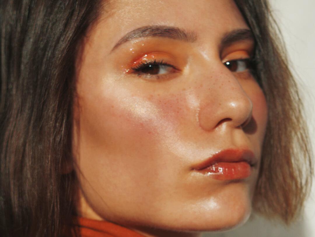Close-up of a beautiful woman rocking a peach monochromatic makeup look Desktop
