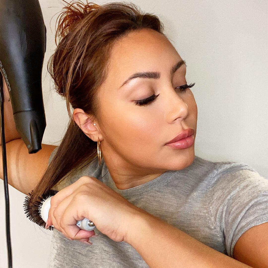Close-up image of Cynthia Alvarez blow-drying her hair with a round brush Mobile
