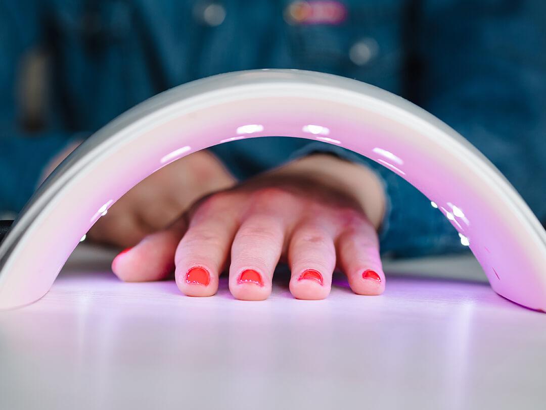 Woman's hand under UV lamp for drying nails Desktop