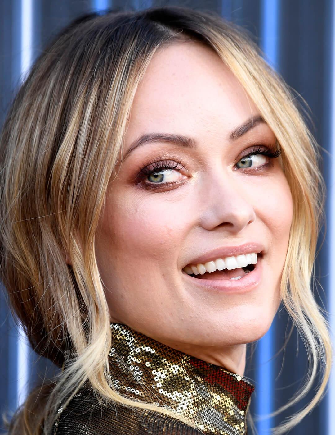 A closeup photo of Olivia Wilde with blonde hair wearing a gold sequin dress Desktop
