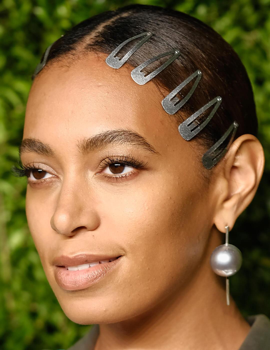 A closeup of Solange Knowles wearing a silk blouse with five dark green hairclips and a big pearl earring Desktop