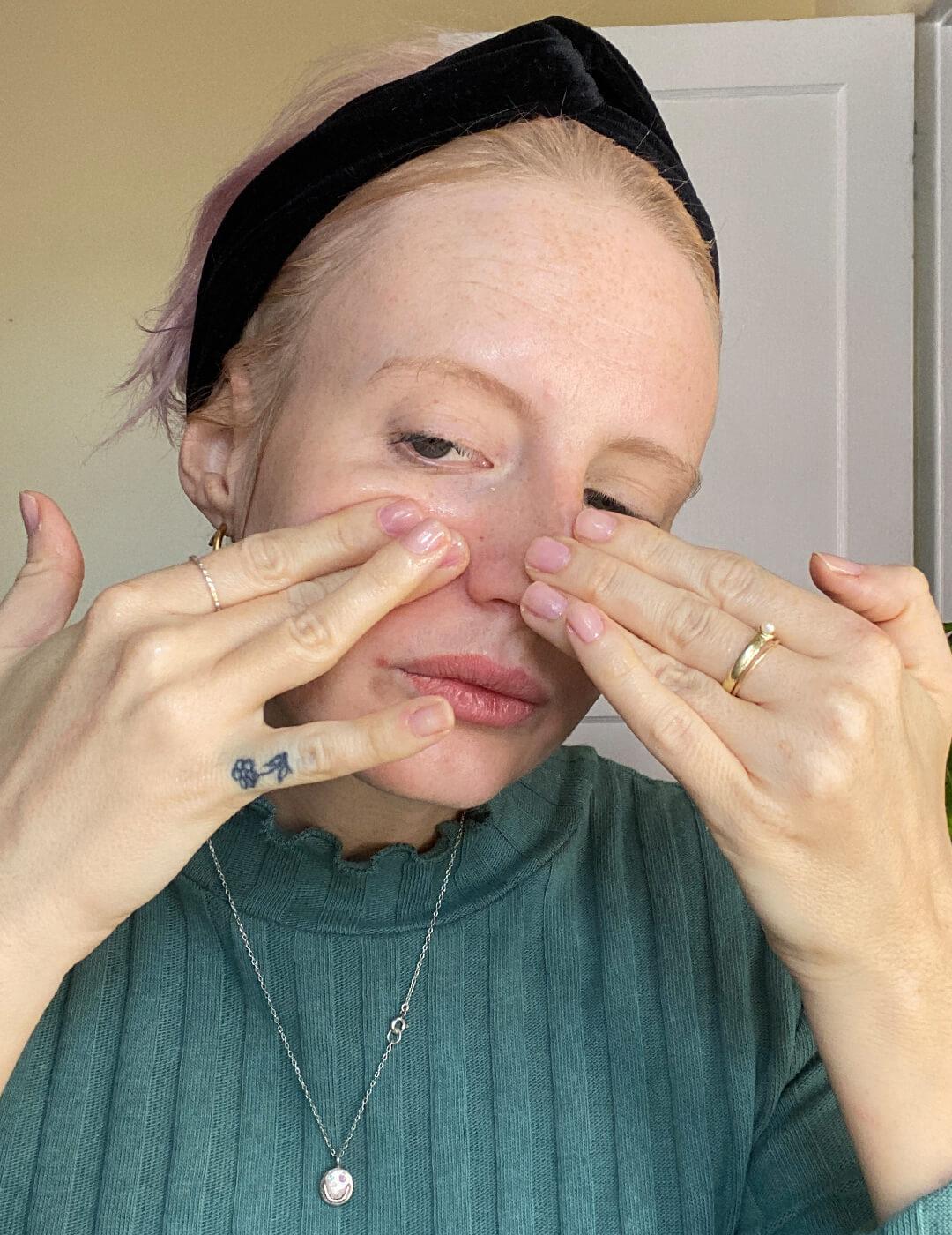 Hannah Cassidy with green sweater and black headband on feeling the side of her nose with her fingers Desktop