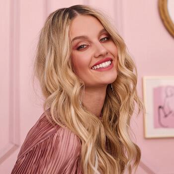 An image of a smiling model with blonde, loose wavy hair Mobile