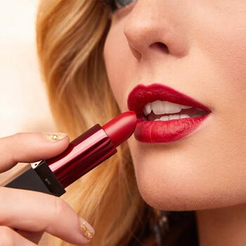 A closeup image of a model putting on bold red lipstick Mobile