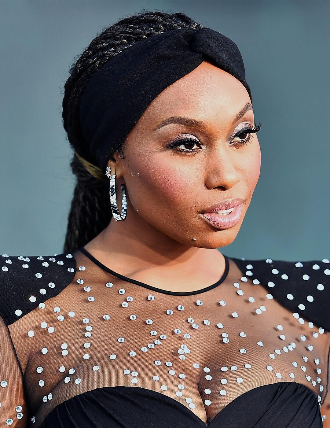 Angell Conwell looking glamorous in a black dress with silver sequin accents and rocking a braided hairstyle with headband Mobile