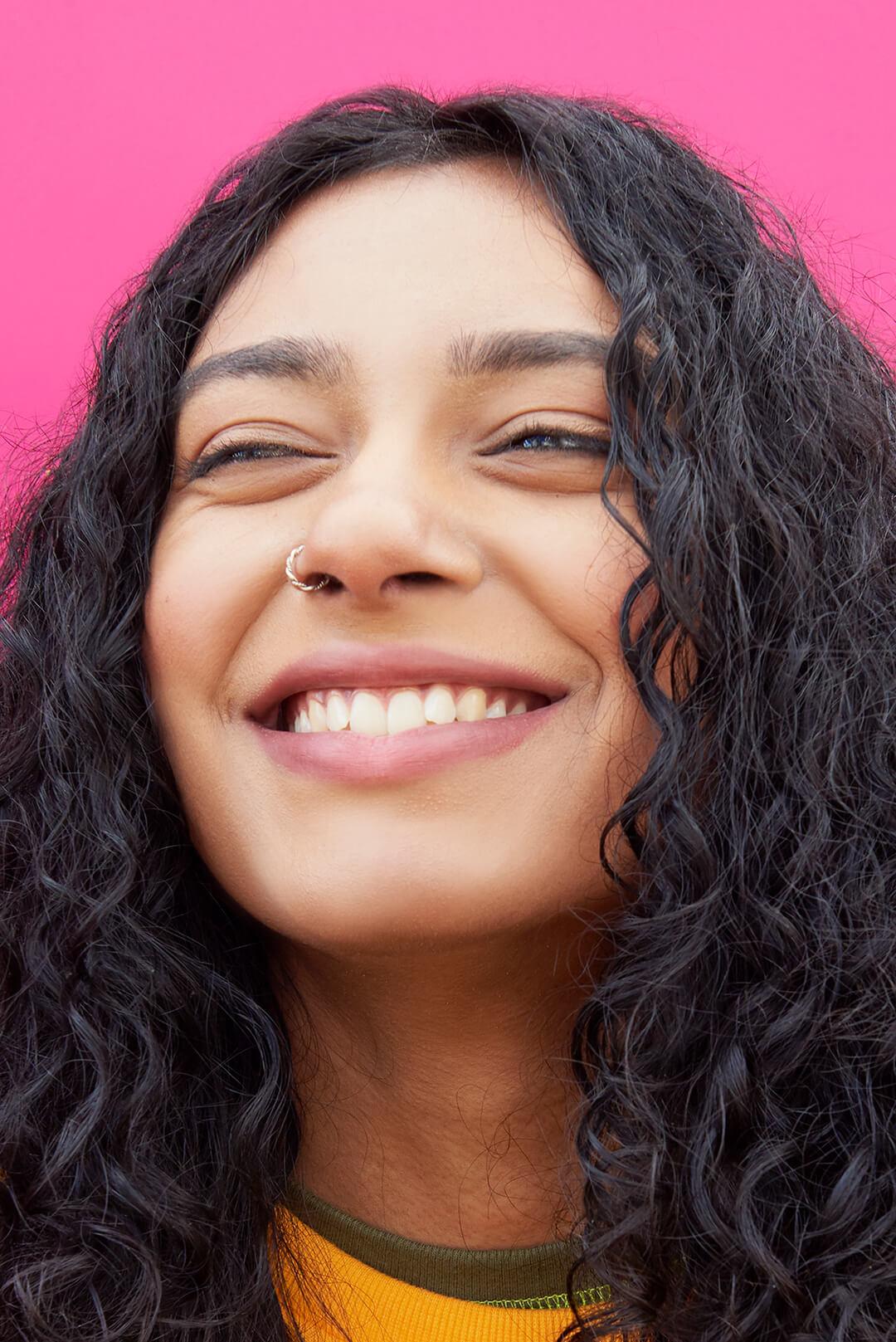 Close-up of a smiling young woman on pink background Desktop