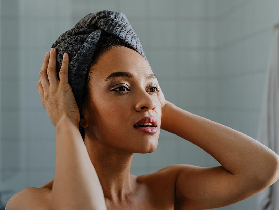 Woman in her bathroom holding her head wrapped in a towel Desktop