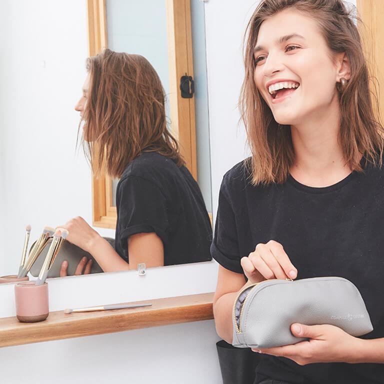 An image of person wearing a black shirt holding a grey makeup bag and a girl in a black shirt smiling Mobile