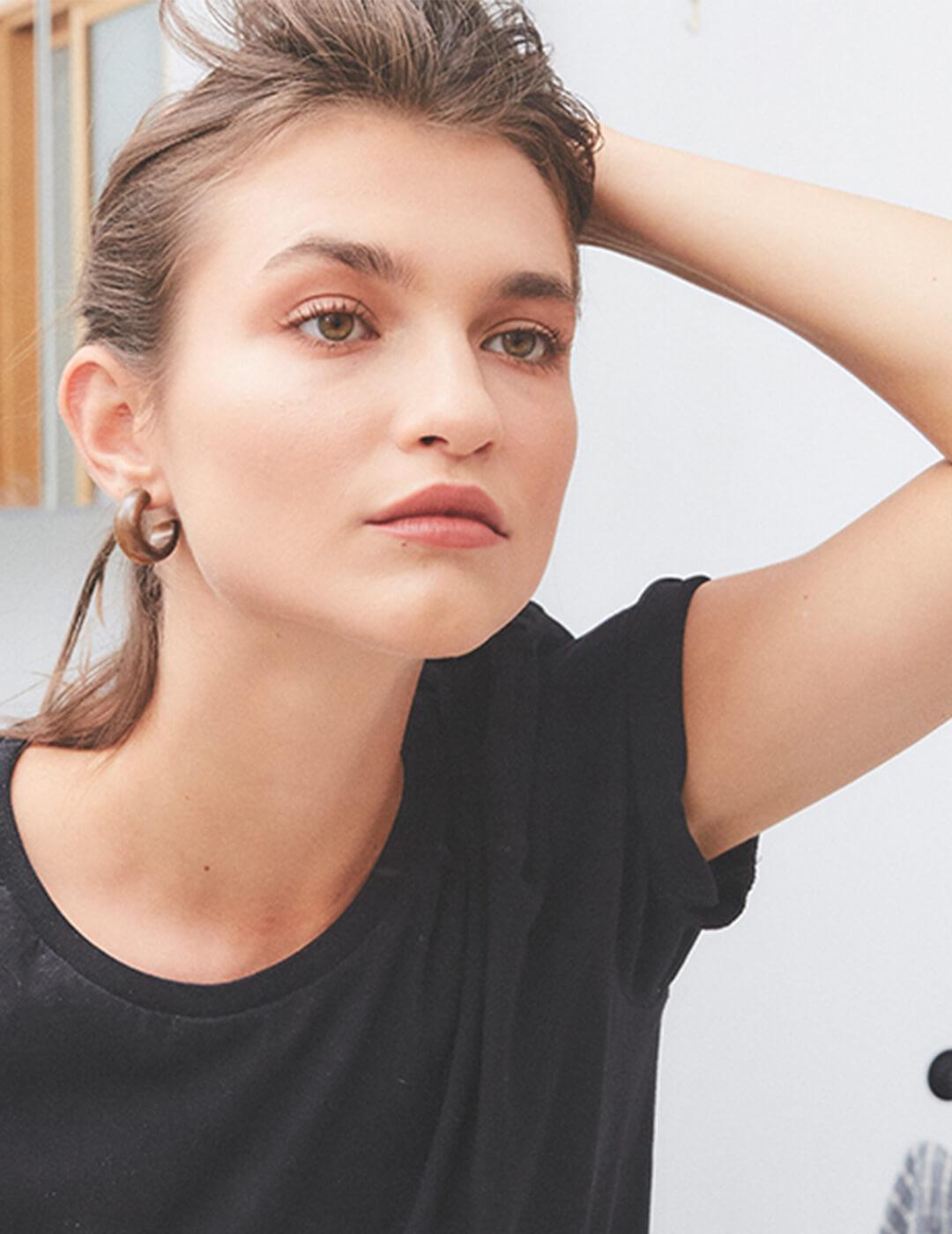A photo of a woman wearing black top looking at the mirror while holding her head Desktop