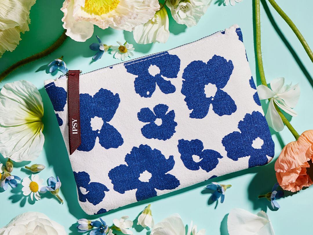 April 2023 IPSY Glam Bag and daisies on light turquoise background Desktop