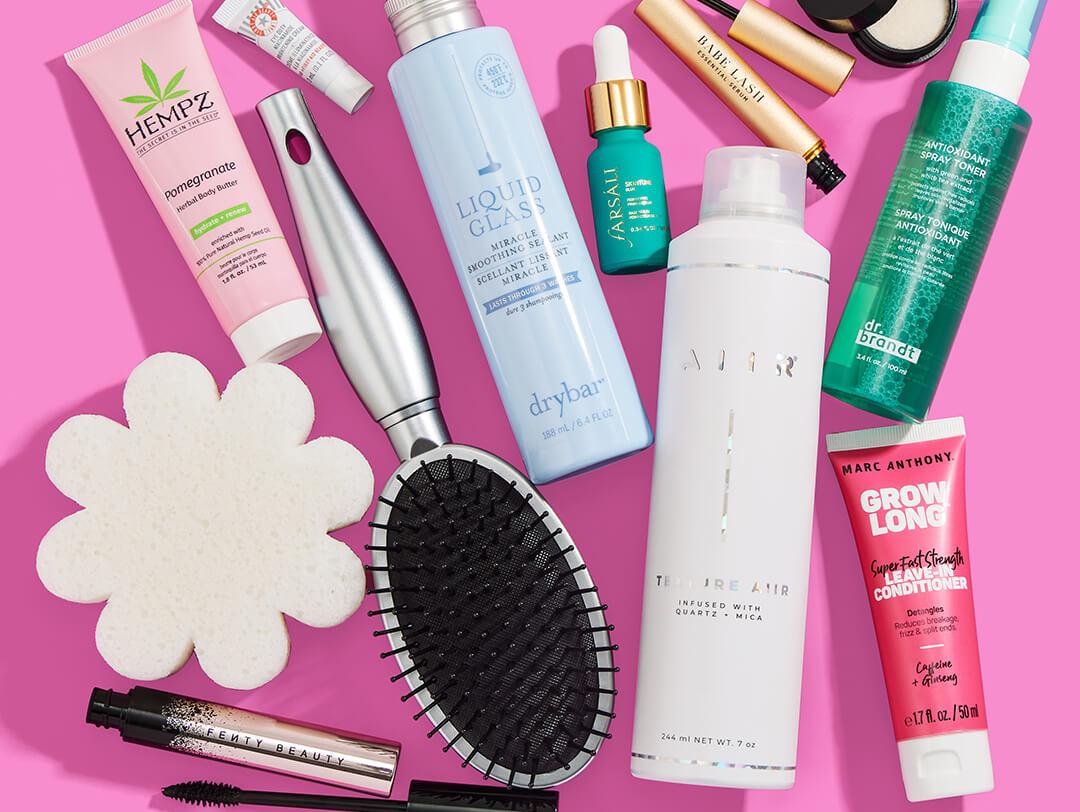 Beauty and makeup products from various brands scattered on pink background Desktop